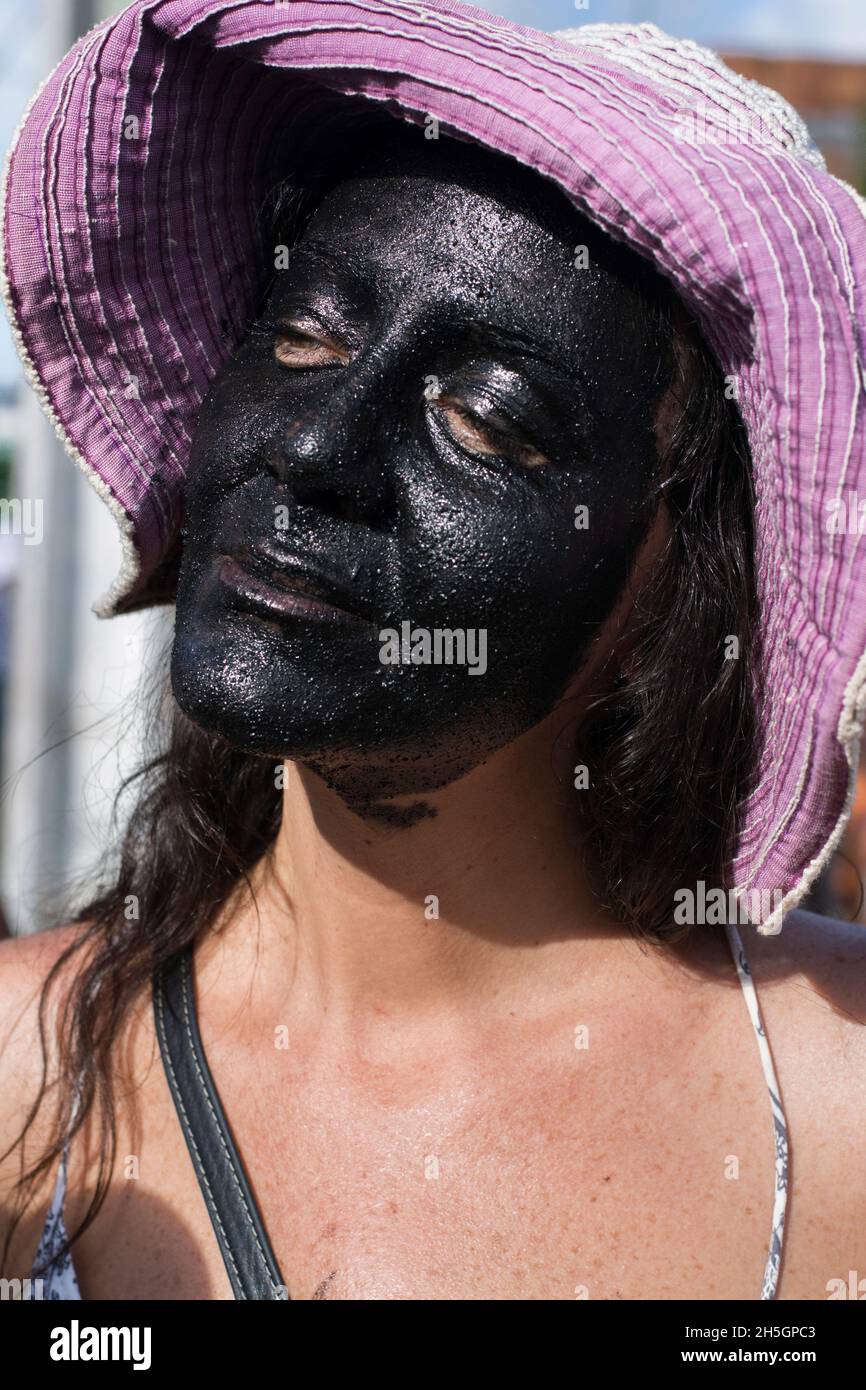 Caucasian woman with face made up in black color. She is wearing a pink colored hat. Acupe, Bahia, Brazil. Stock Photo