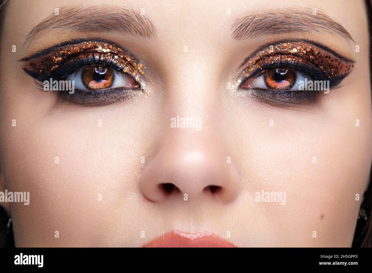 Closeup shot of female face with vogue golden shining eyes makeup