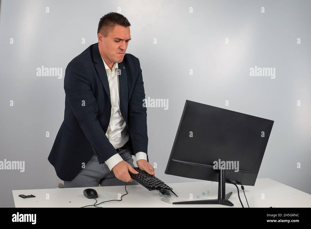 Caucasian man in a suit gets angry and smashes the keyboard on the