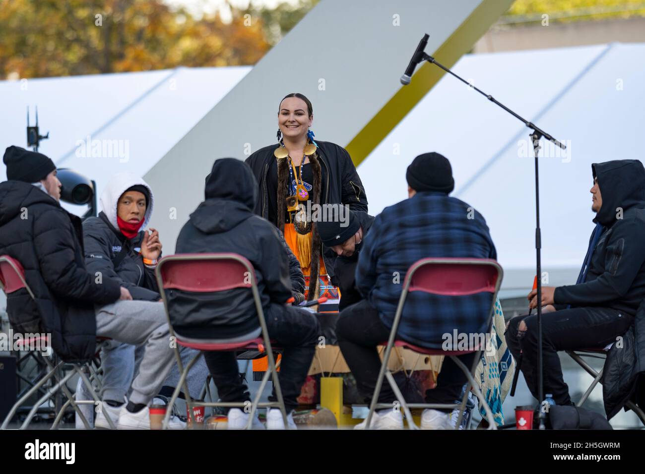 Young Indigenous Woman Danielle Migwans with All Nation Big Drum singers / drummers at Indigenous Legacy Gathering November 4, 2021 Toronto, Canada Stock Photo