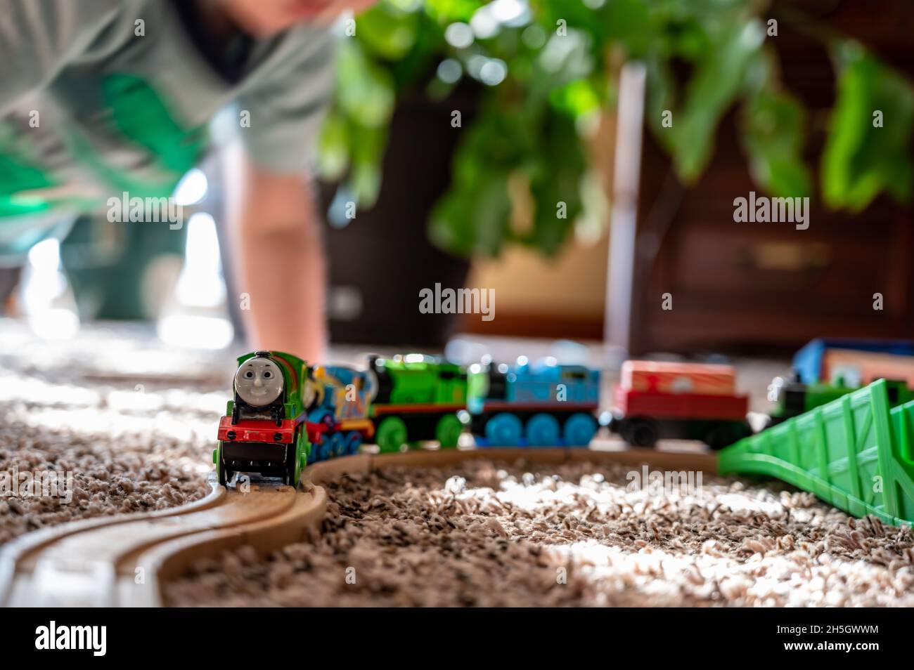 Tiffin, Iowa, USA - 3.2021: Small boy playing with a model Thomas the Train. Thomas is a popular railroad themed children's' toy.  Stock Photo