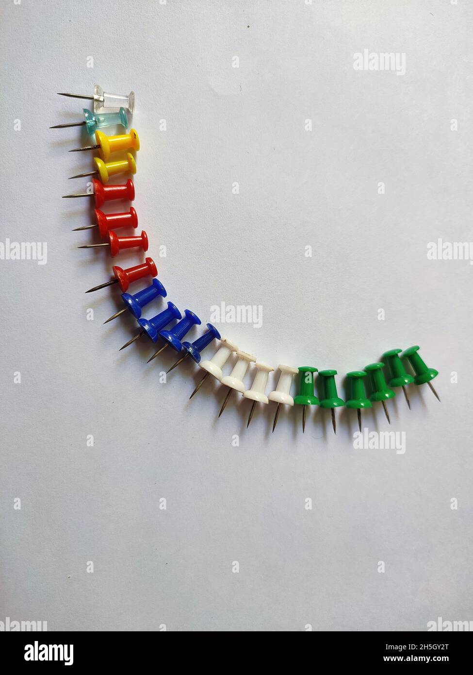Row of drawing pins on white background Stock Photo - Alamy