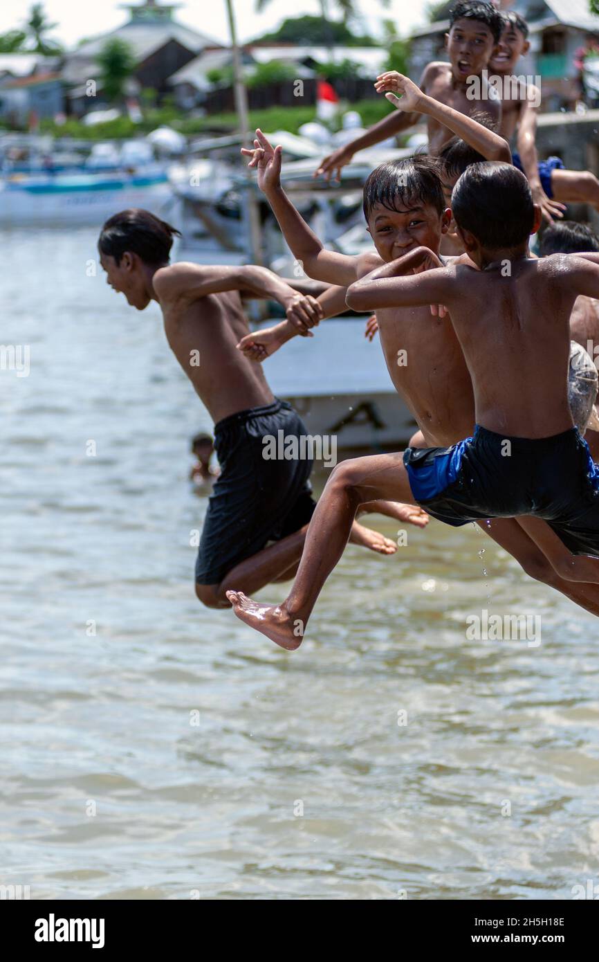 Kids jumping off ferry crossing in sumbawa pier,Indonesia Stock Photo
