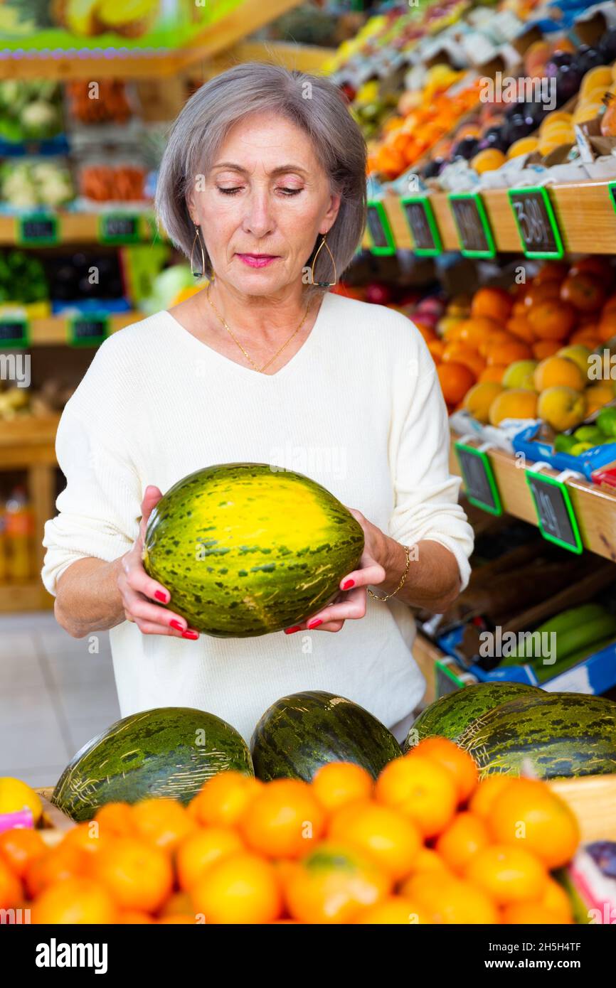 Senior woman choosing melon in greengrocer Stock Photo Alamy