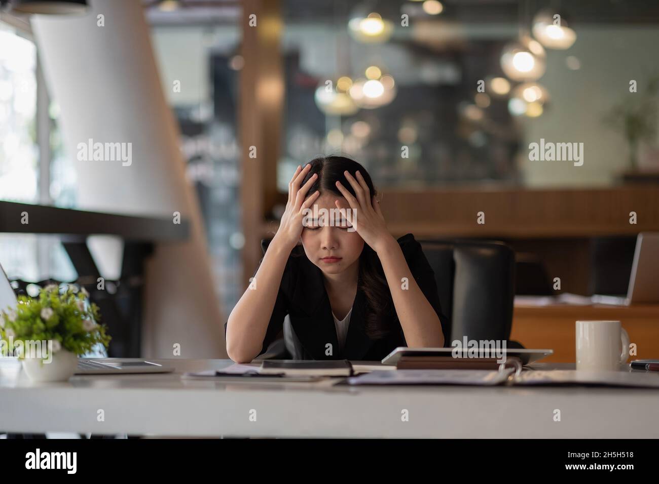 Stressed business woman working on laptop looking worried, tired and overwhelmed. asian female headache suffer from bad blurry weak vision tired of Stock Photo