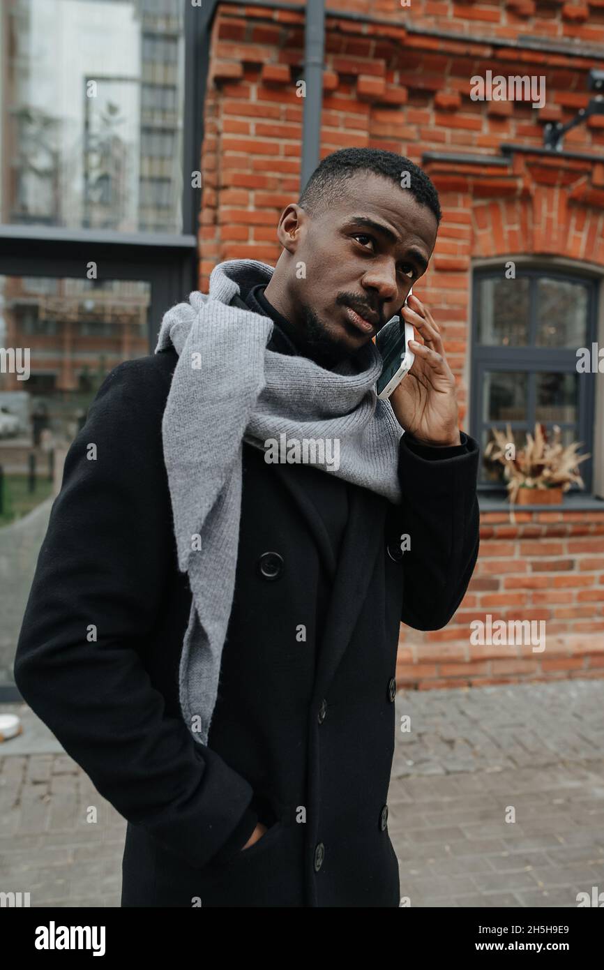 Black man dressed for autumn talking on the phone on the street