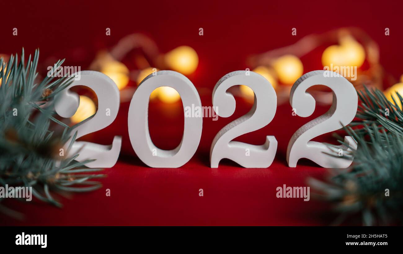 Happy New Year 2022. White Wooden Numbers 2022 Stand With Christmas Tree Branches On Red Background With Garland Light Bulbs. Merry Christmas Stock Photo - Alamy