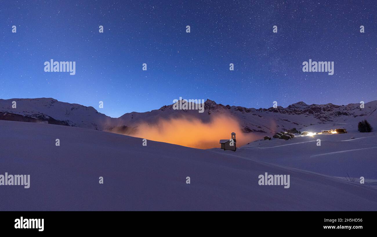 Starry night on snowcapped mountains and huts at Chrismas time, Andossi, Madesimo, Valchiavenna, Valtellina, Lombardy, Italy Stock Photo