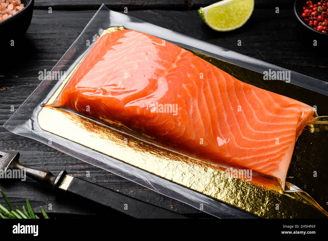 Salmon fillet in a vacuum plastic pack set, with herbs, on black wooden ...