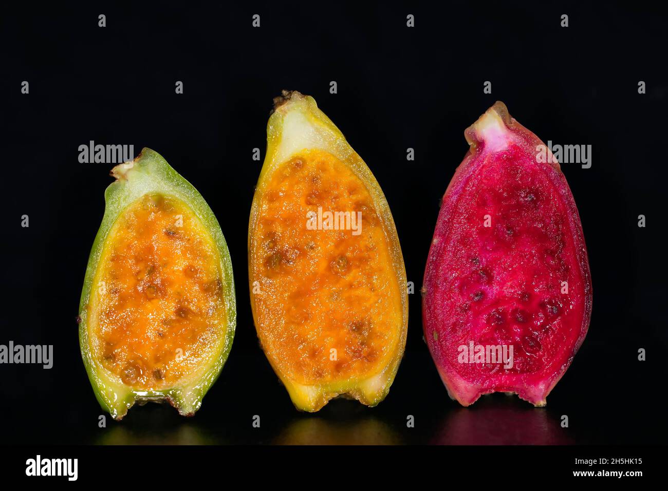Halved cactus fruits in three different states of ripeness, studio photography with black background Stock Photo