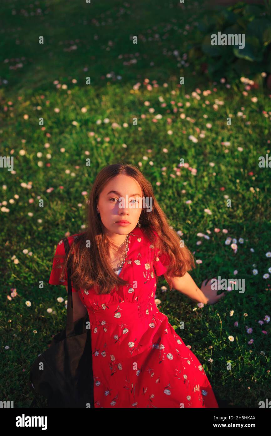 Young beautiful gir in red dress isl resting on fresh spring grass Stock Photo