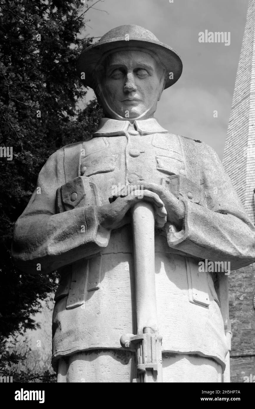 World War One British or Commonwealth soldier at prayer with rifle reversed, statue in stone in an English village churchyard. Stock Photo