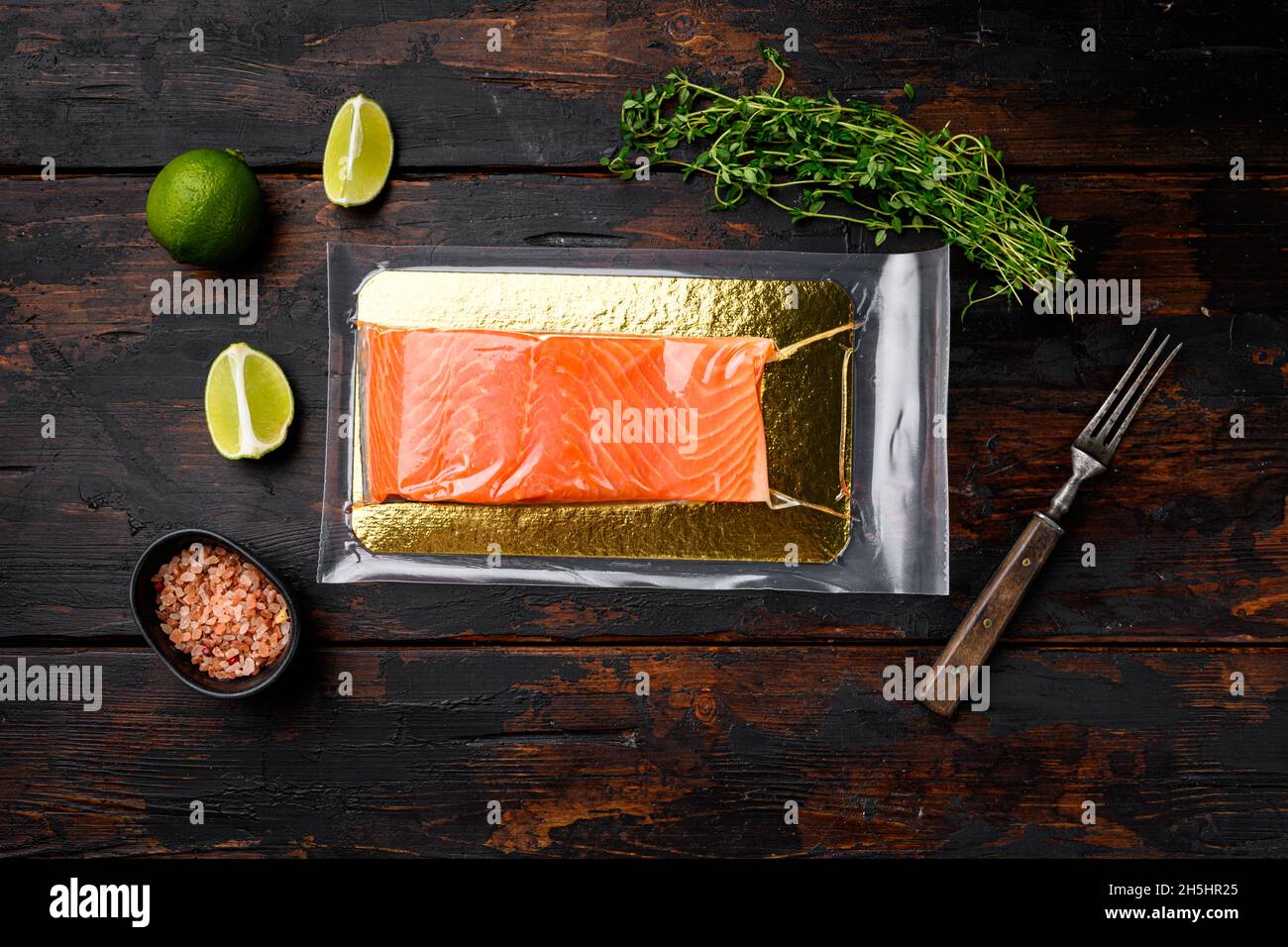 Red fish fillet in vacuum pack set, with herbs, on old dark wooden