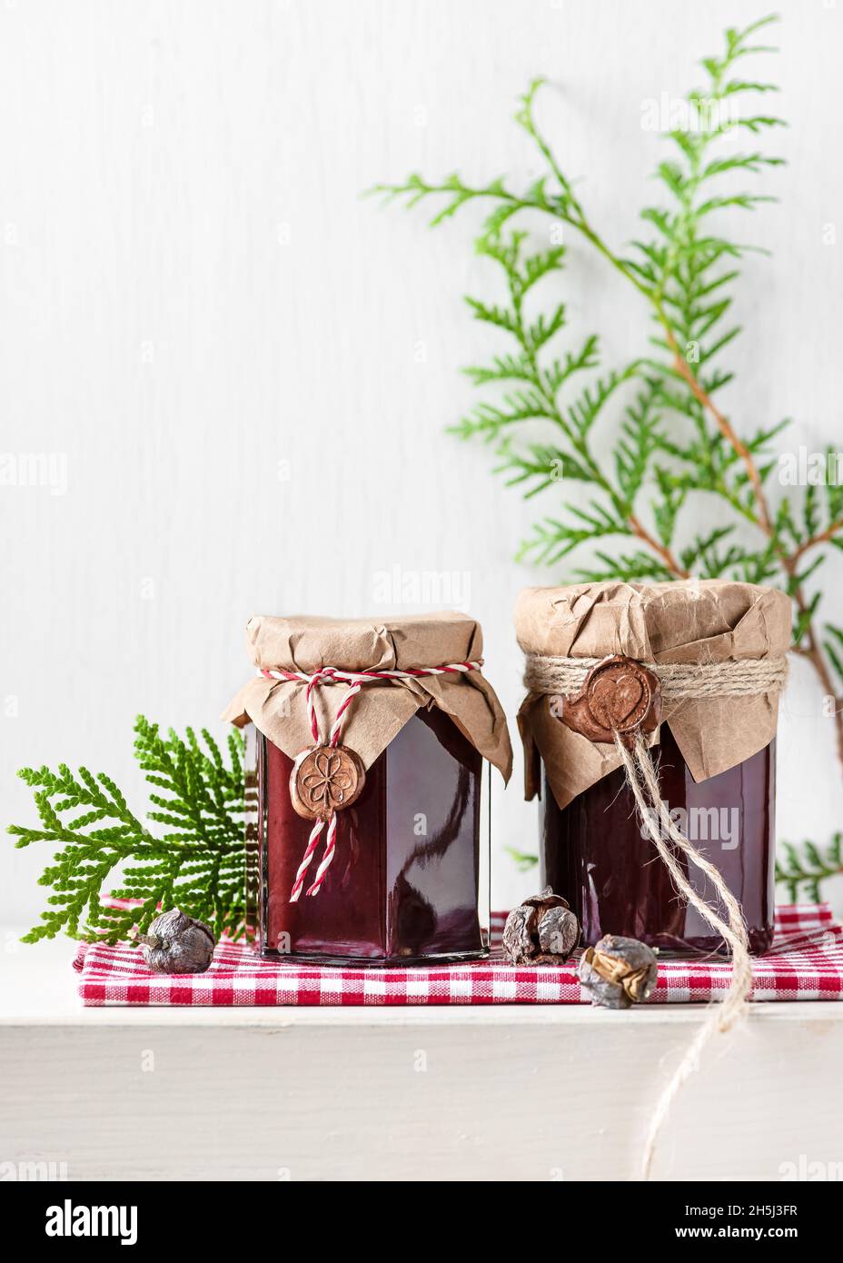 Homemade fruit jam in the glas jars decorated with grunge paper and wax seal as small present for Christmas. Kitchen gift ideas concept. Copy space. Stock Photo