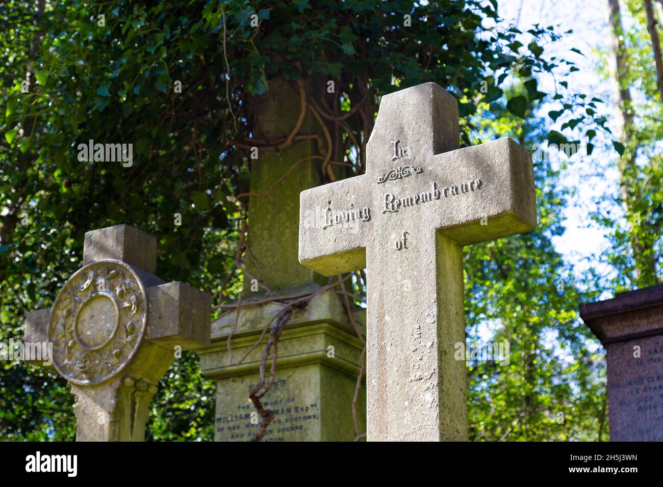 Chipped cross with text 'In Loving Remembrance of' at Highgate Cemetery West, London, UK Stock Photo