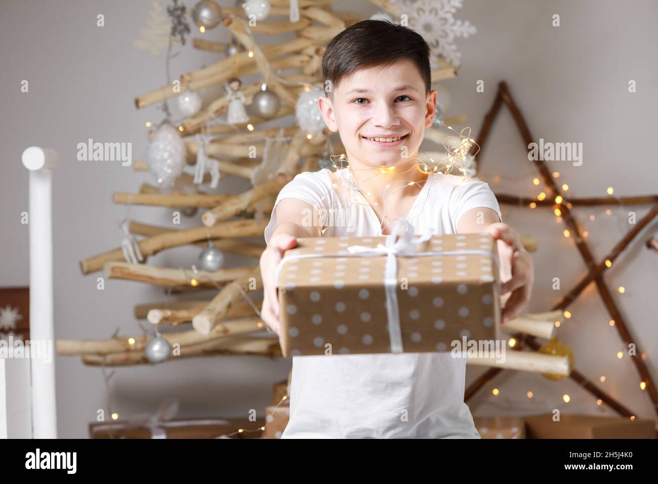Holidays Concept. Cheerful teenage boy giving gift box on camera