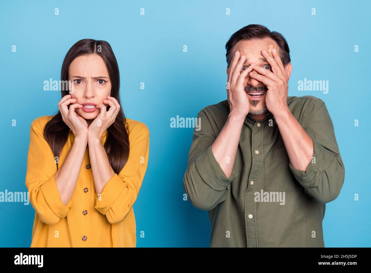 Photo of worried astonished shocked mature man and woman hold hands face nail bite isolated on blue color background Stock Photo