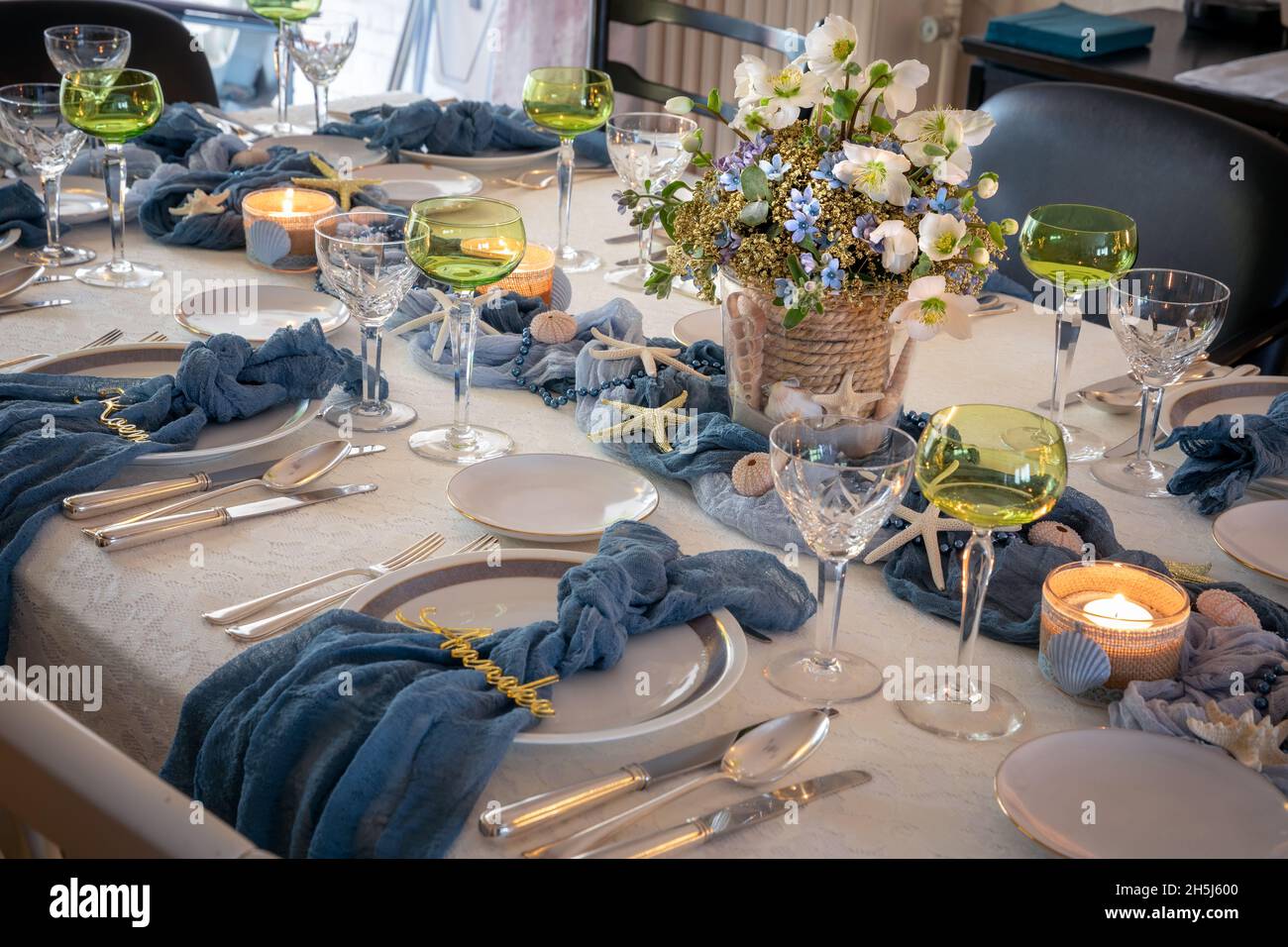Christmas dinner table decorations in blues and gold following a beach theme with seashells and starfish Stock Photo