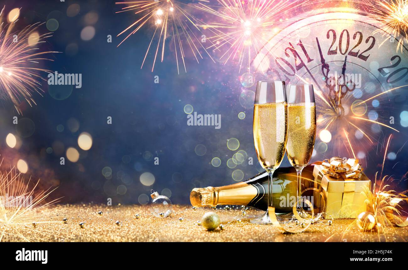 New Year Celebration 2022 - Champagne With Clock And Fireworks At Night - Countdown To Midnight - Abstract Defocused Background Stock Photo