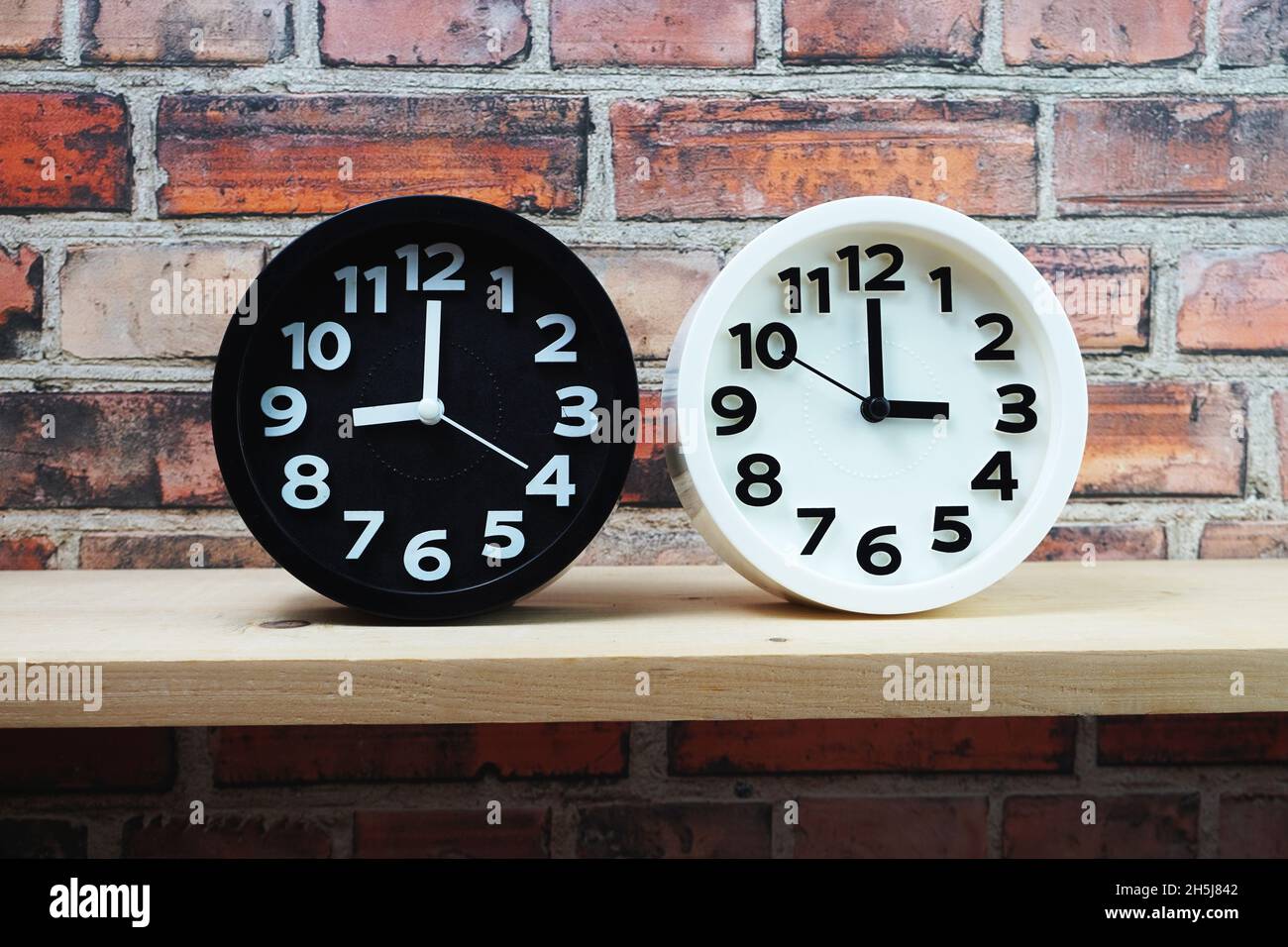 Clocks with time zone of different country on wooden shelves and brick