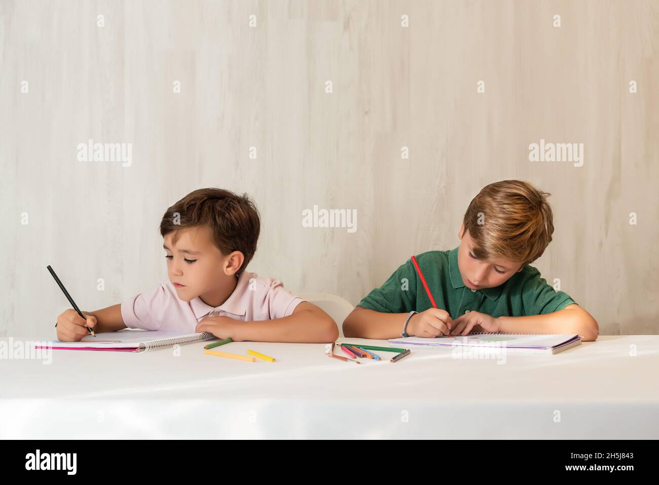 Two children doing homework at school, drawing with crayons Stock Photo