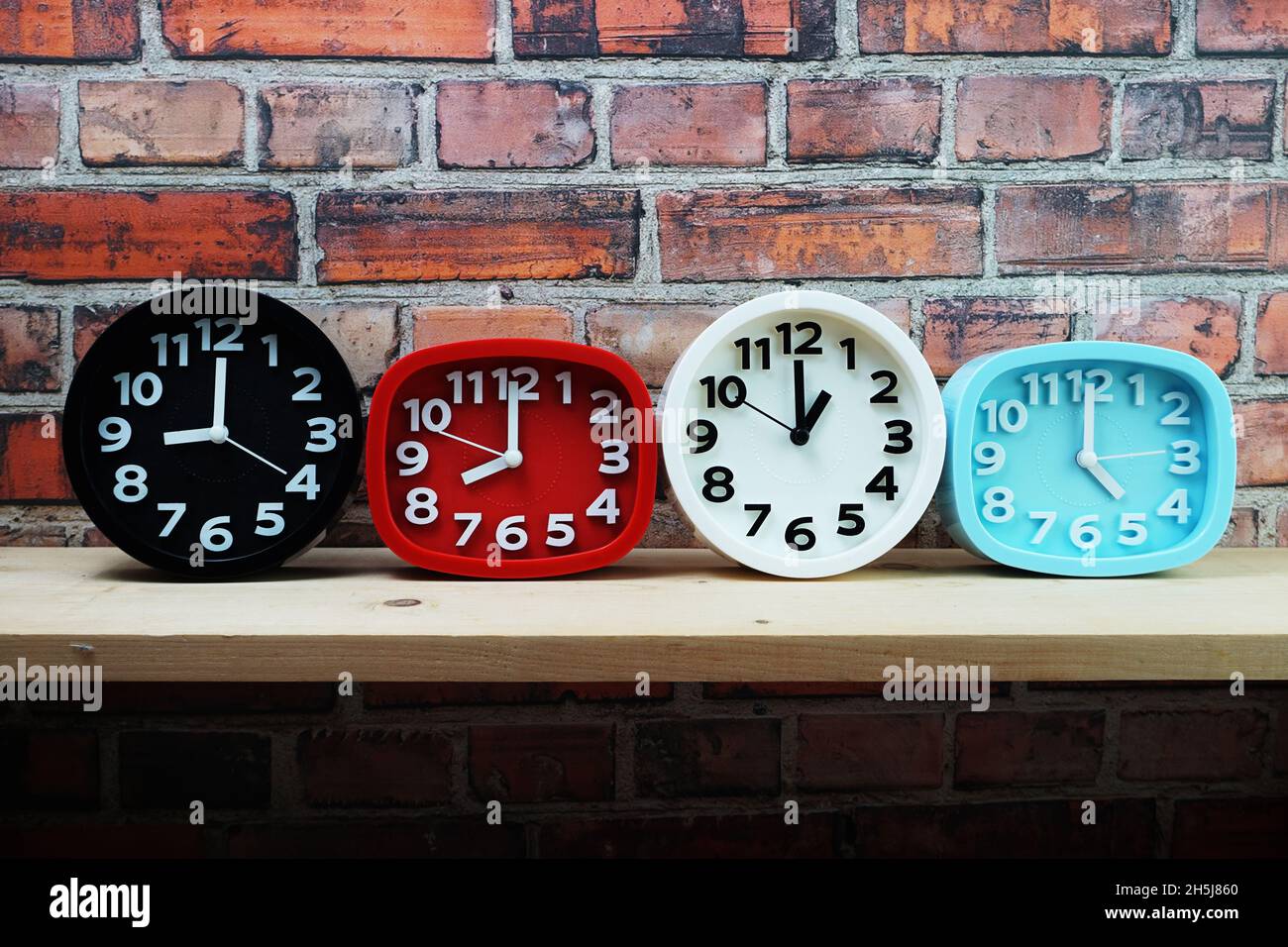 Clocks with time zone of different country on wooden shelves and brick