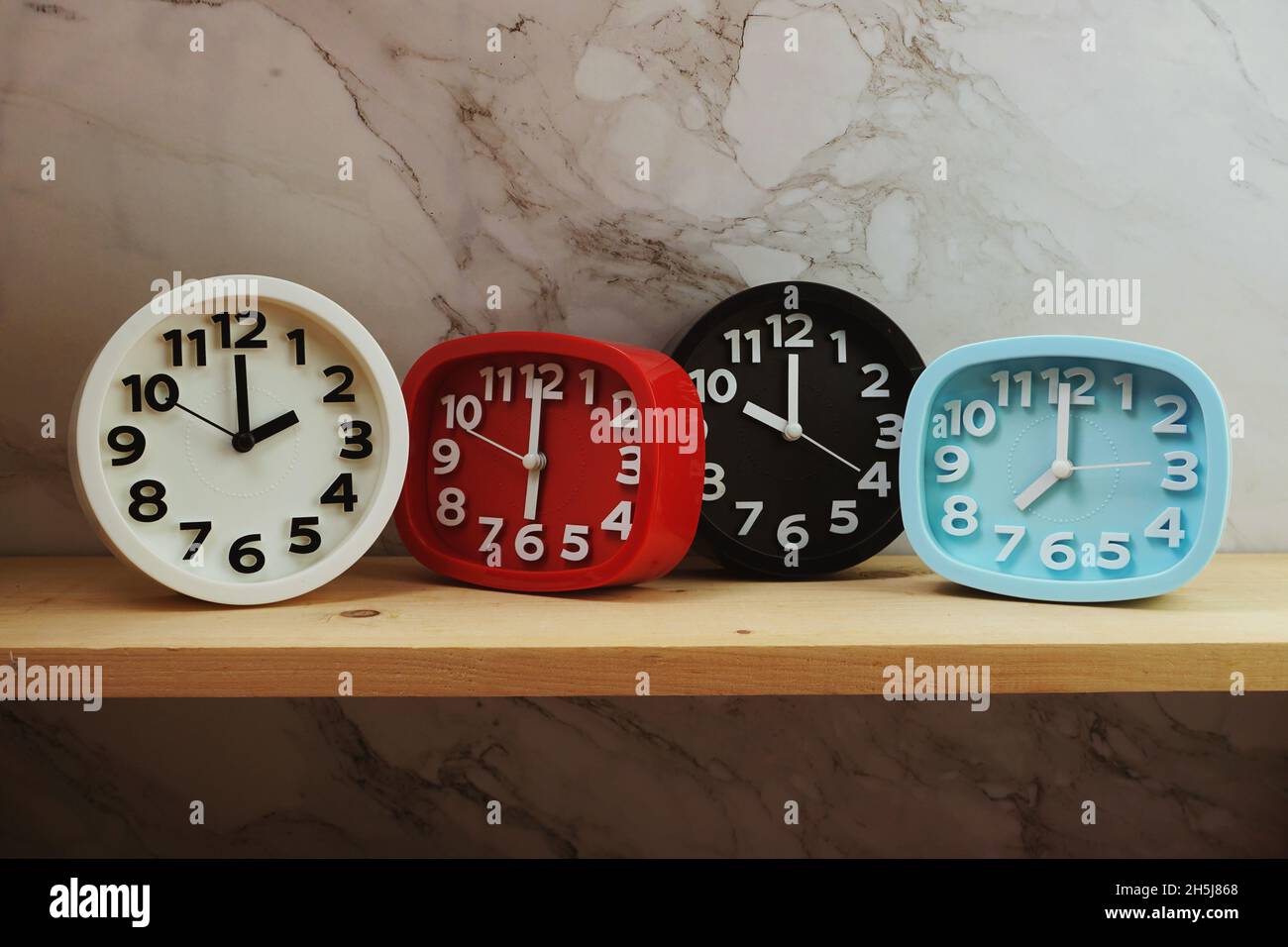 Clocks with time zone of different country on wooden shelves and marble