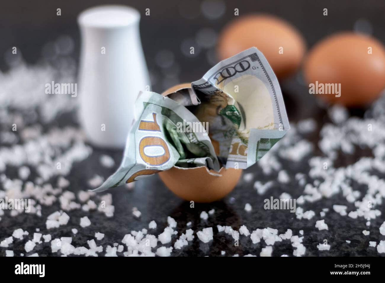 A dollar bill in a cracked egg shell - as a symbol of over-enrichment of a small, narrow group of the population - even while eating breakfast. Stock Photo