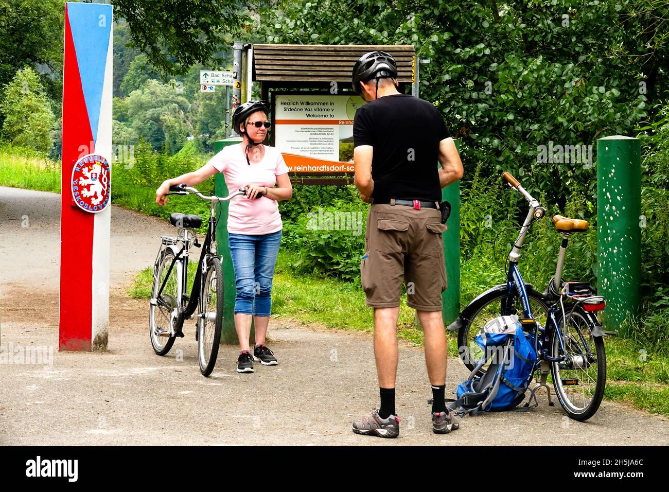 Cyclists on cycle route in the Elbe valley, Czech-German border crossing with a sign Stock Photo