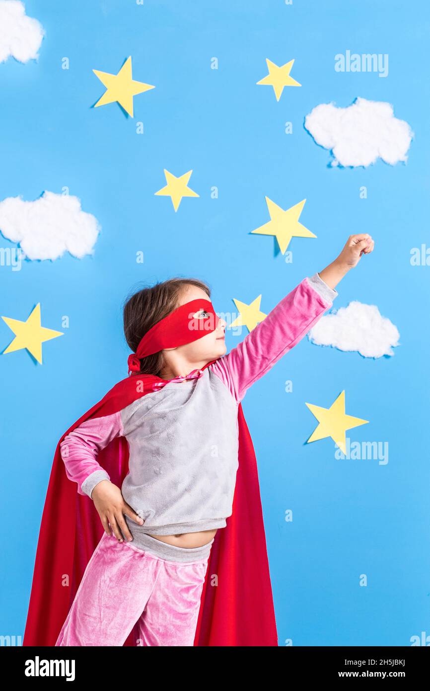 Little child plays superhero. Kid on the background of bright blue wall ...