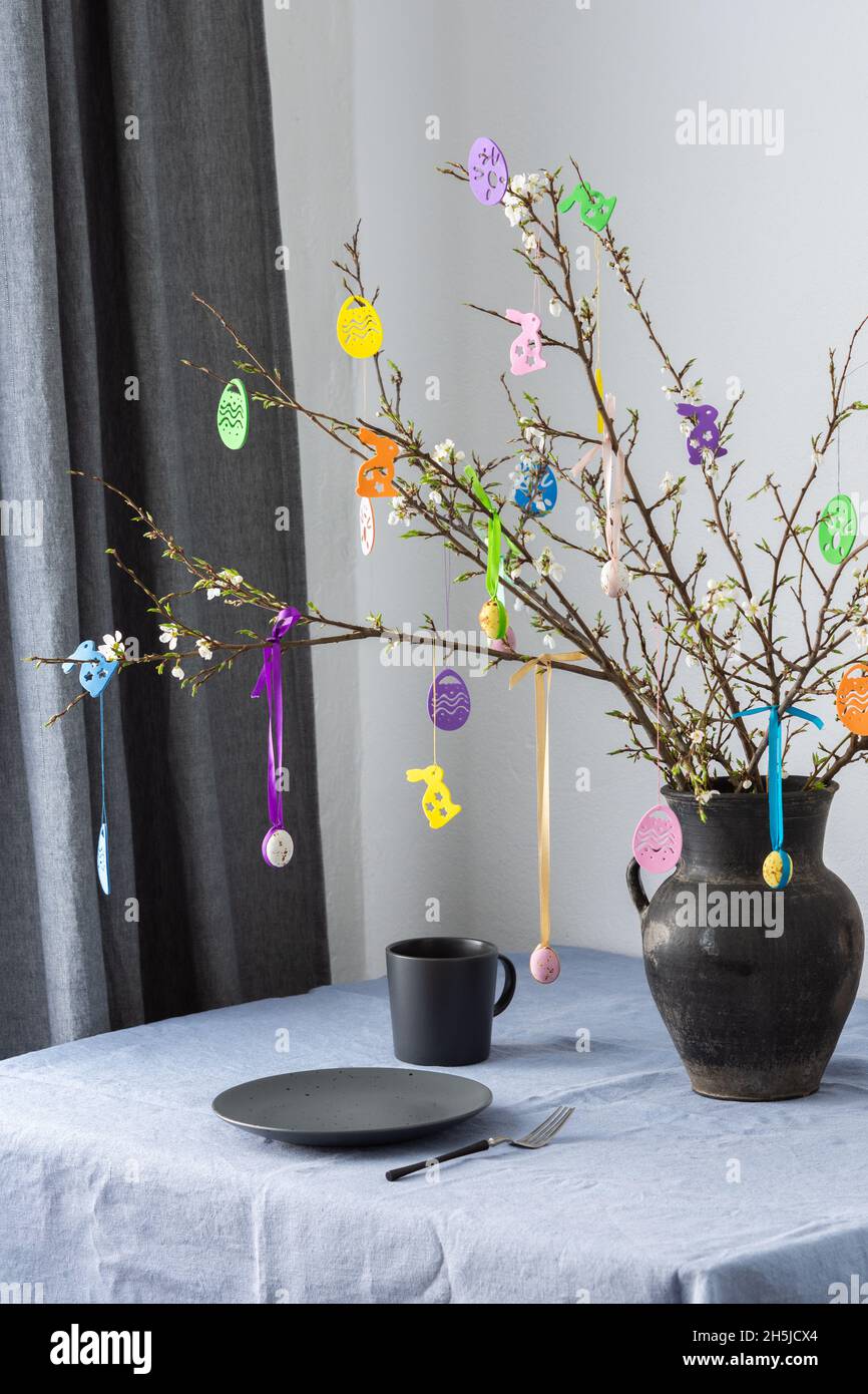 Blooming cherry branches decorated with colorful ribbons with Easter eggs, Happy Easter, table setting Stock Photo