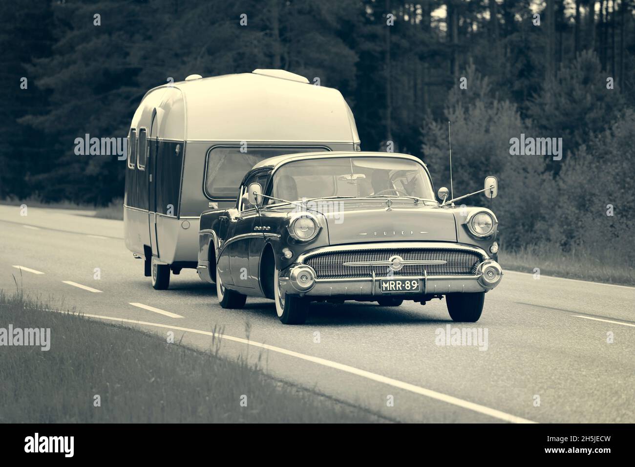 Beautiful Buick Special classic car, year 1957, pulling a matching caravan on highway in the summer. Old photo look. Salo, Finland. June 24, 2021. Stock Photo