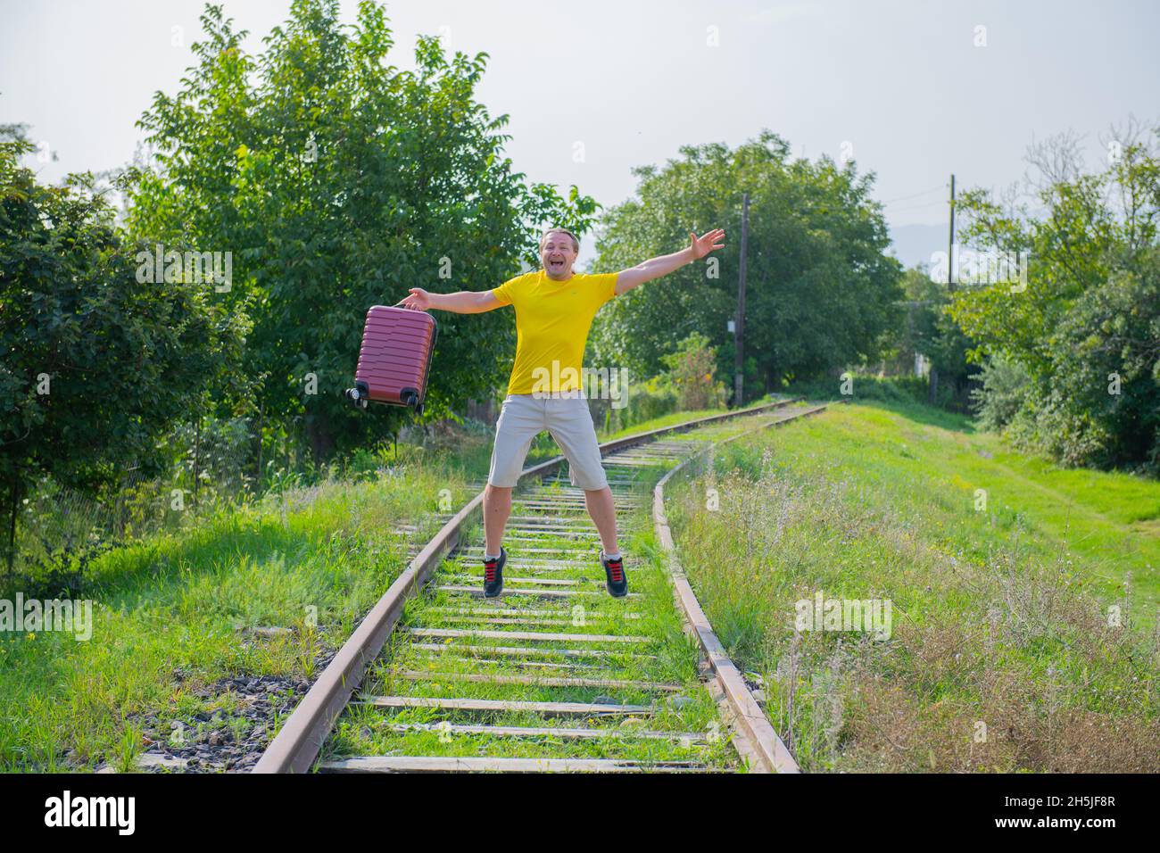 guy with a suitcase jumping on the railroad Stock Photo Alamy