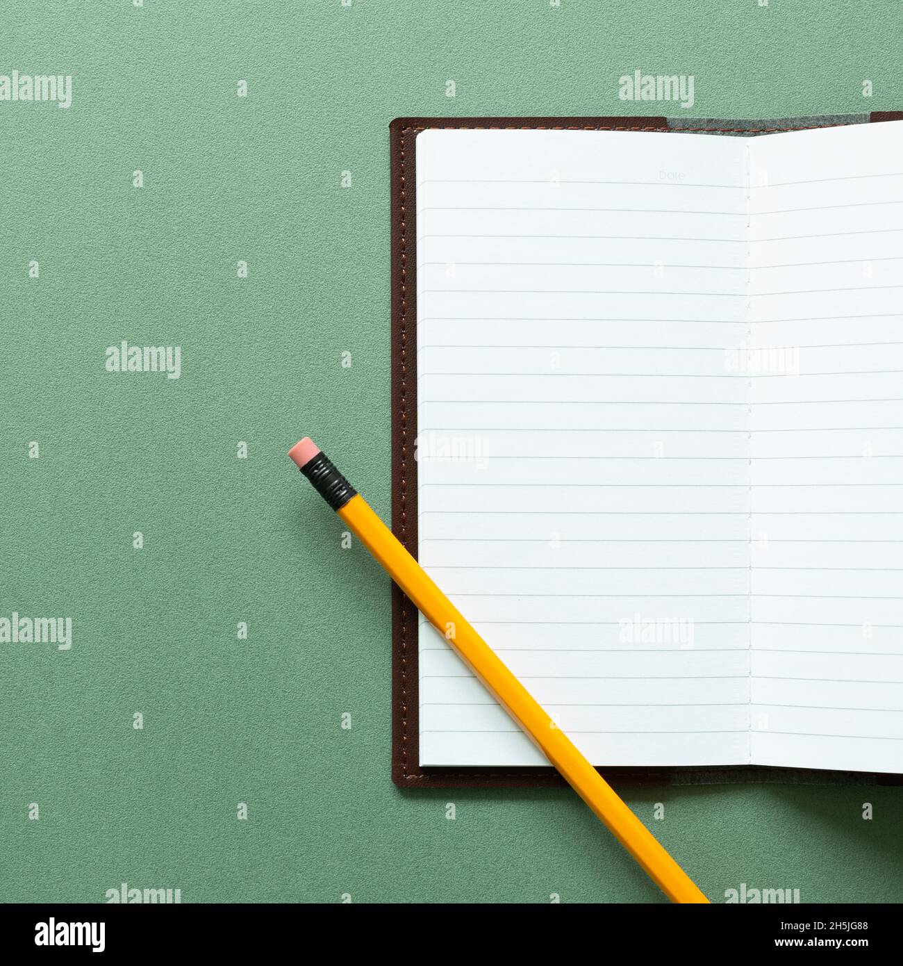 Open notebook and pencil on green background. top view, copy space Stock Photo