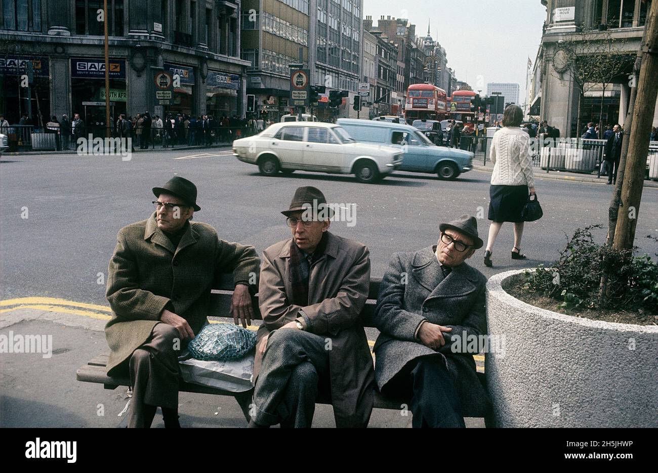 London 1982. A street view of Oxford Circus with three men in coats sitting on a bench. Credit Roland Palm. Stock Photo