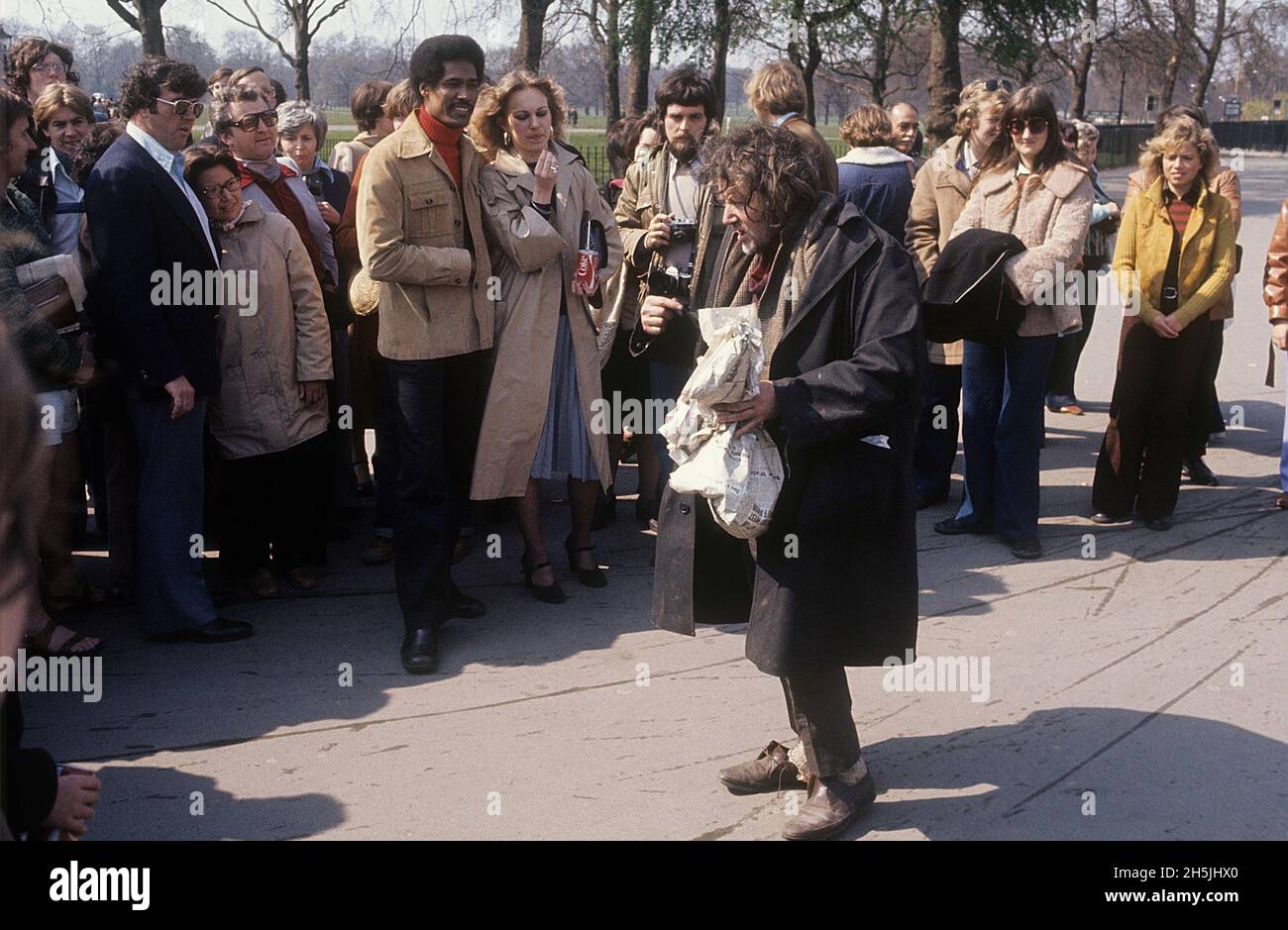 London 1982. A street view of a a seemingly drunken and homeless man who is performing something in front of a group of people. Credit Roland Palm. Stock Photo