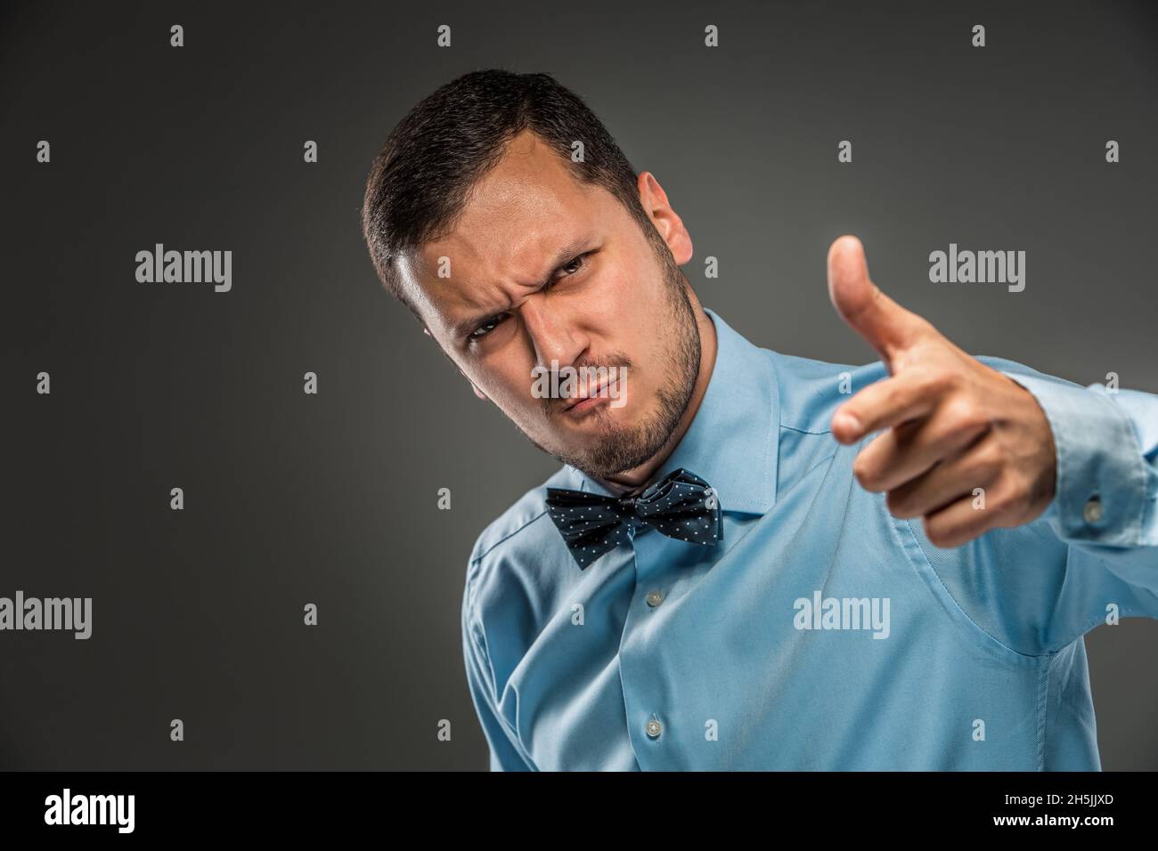 Portrait angry upset young man in blue shirt, butterfly tie Stock Photo