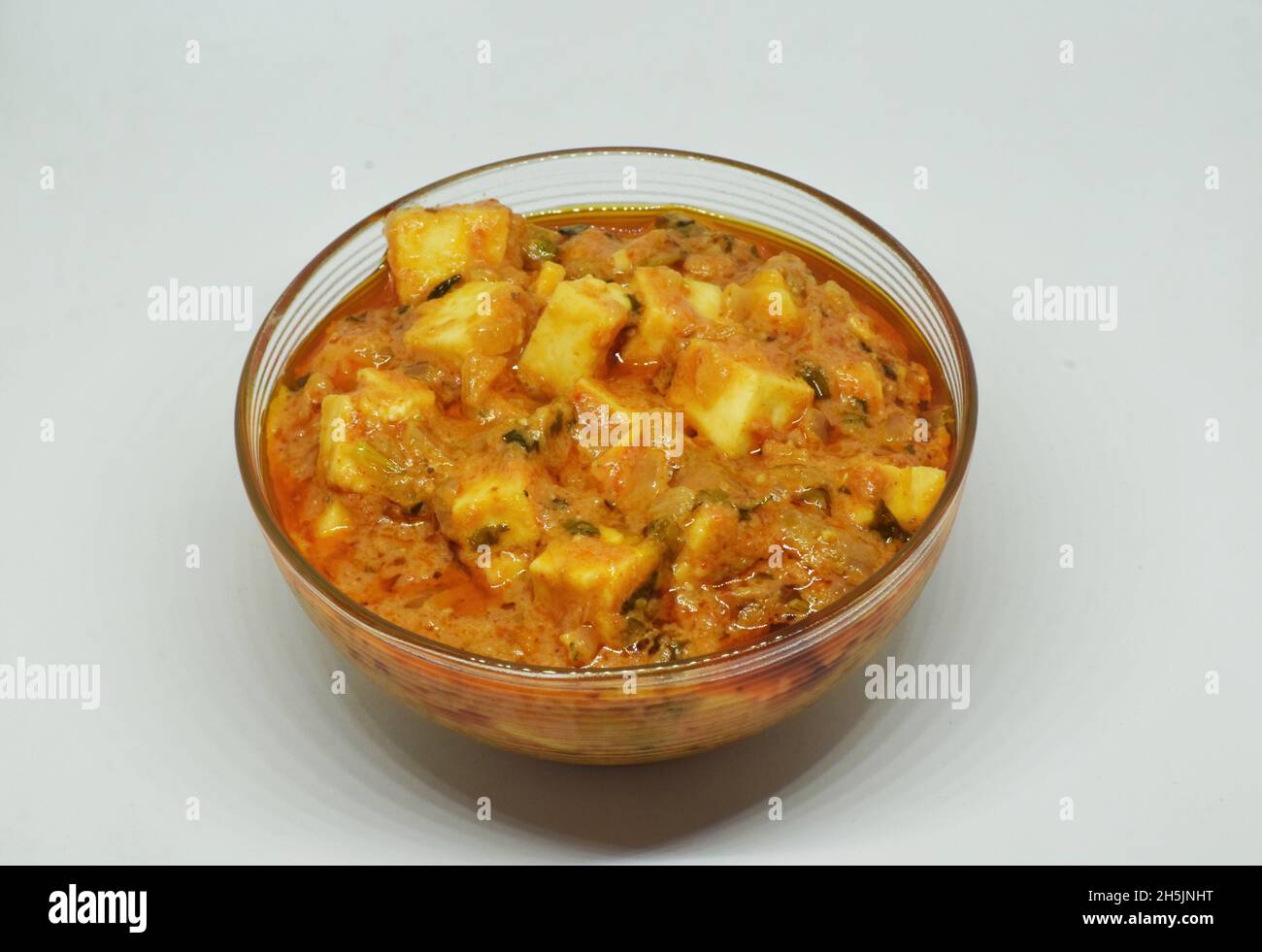 Serving of Indian Kadai paneer in a transparent bowl on a white