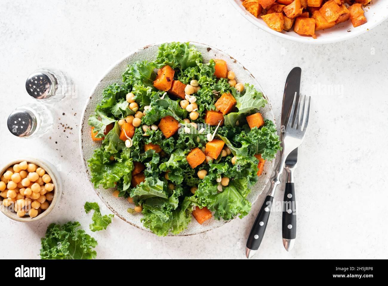Healthy vegan salad bowl with roasted sweet potato and kale, table top view Stock Photo