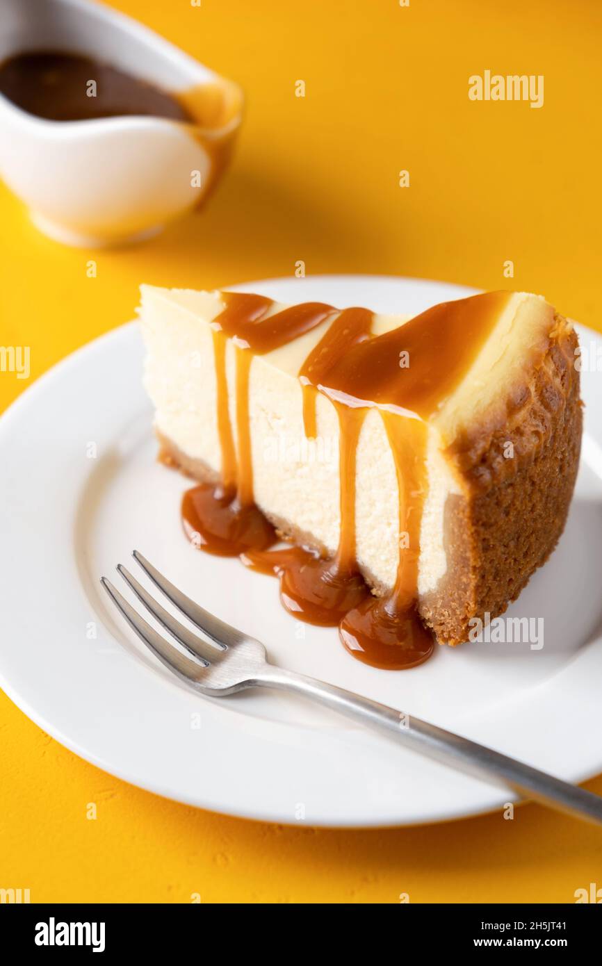 Slice of cheesecake with caramel sauce, yellow background Stock Photo