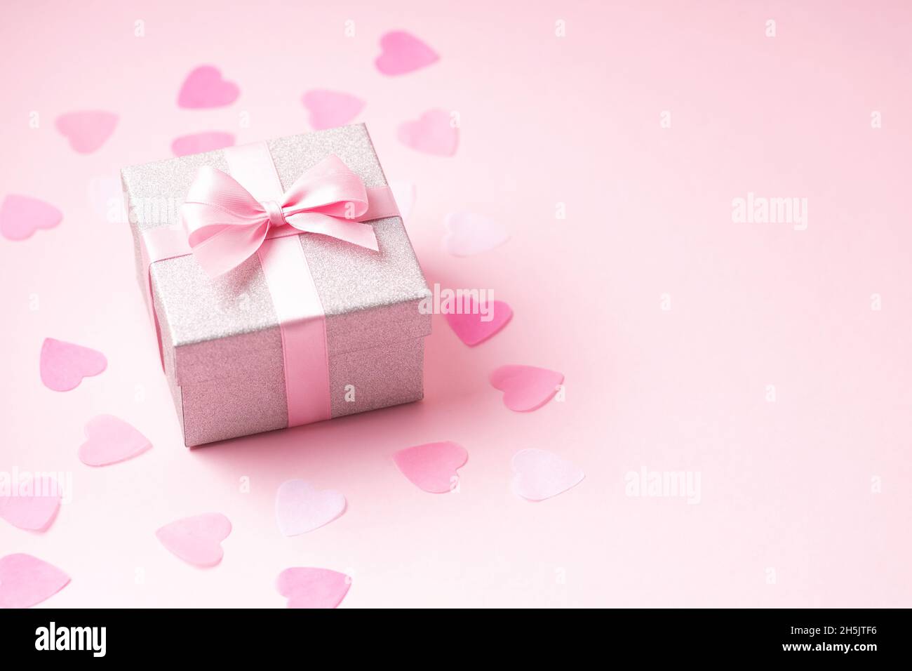 Silver glitter with pink ribbon bow on pink background with heart ...