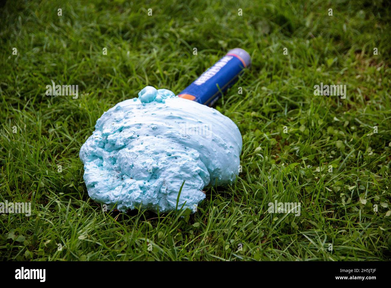 An exploded cylinder with construction foam on the grass. Balloon