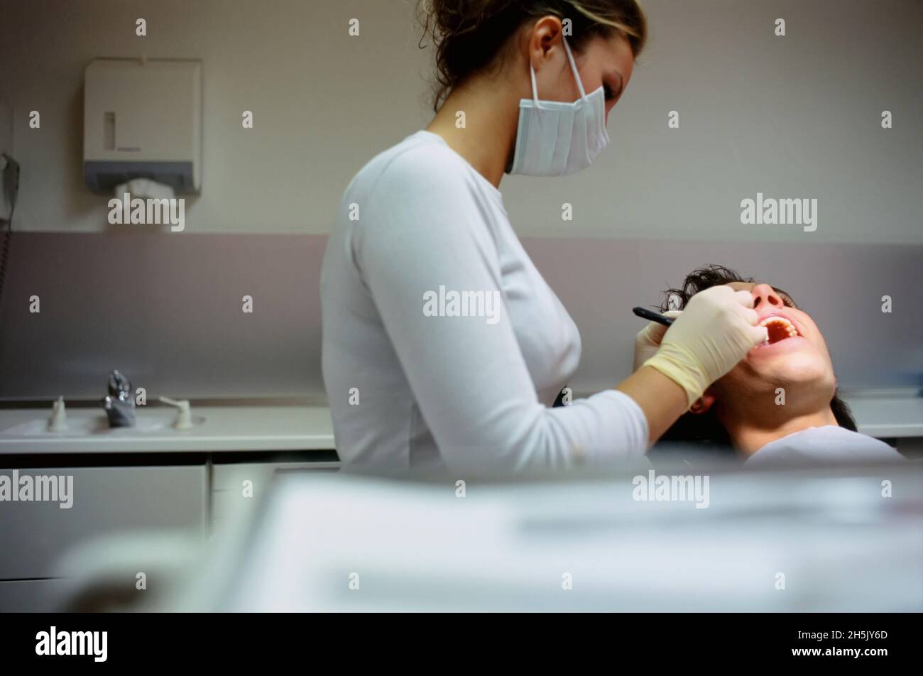 Dentist working on patient's teeth inside dental office; Germany Stock Photo