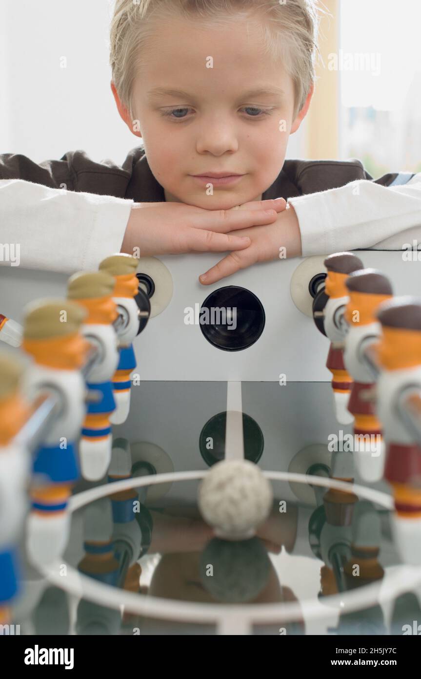 Boy looking longingly at foosball game; Germany Stock Photo