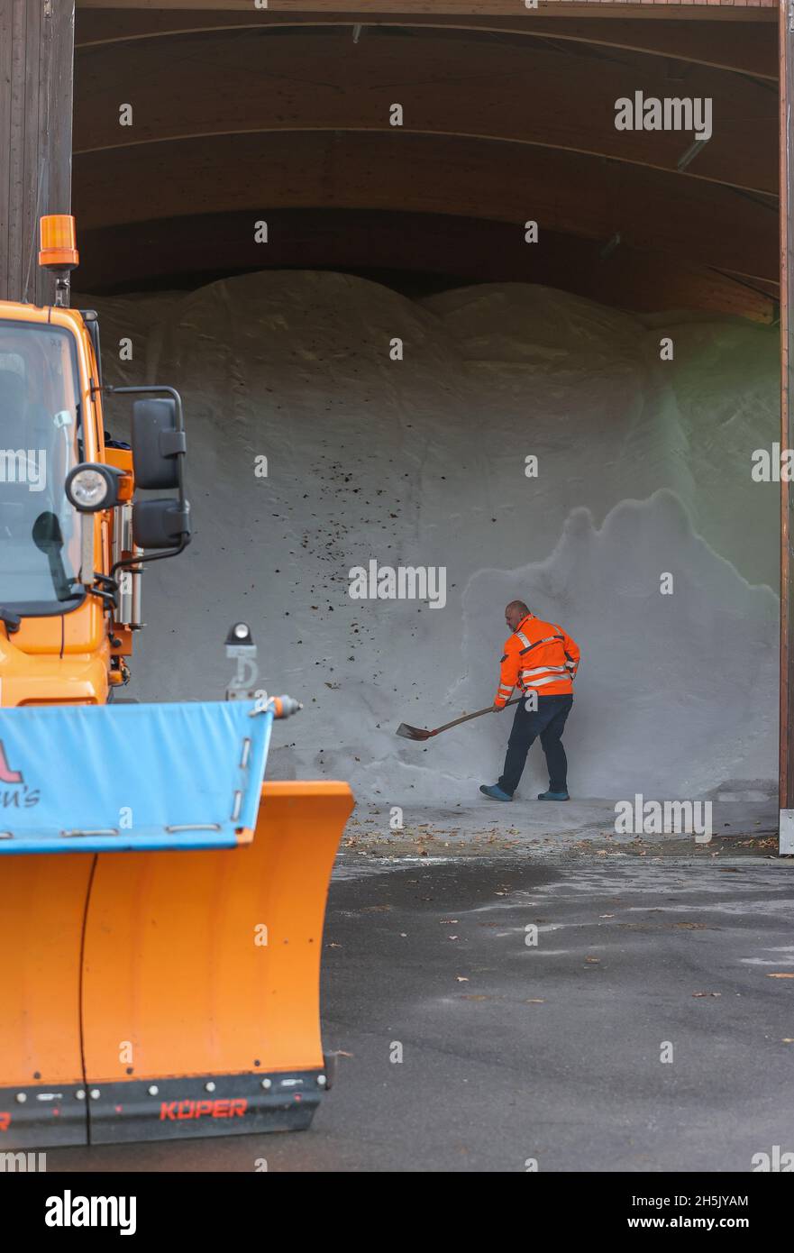 10 November 2021, Saxony, Zwickau: Road maintenance worker Sandro Wichmann shovels road salt, which was spread during loading, back onto the large pile in the salt storage hall. The hall stores 1,000 tons of road salt, the district has stored 3250 tons for the winter and has concluded contracts for the supply. The road maintenance department looks after 789 kilometres of country, state and county roads with 25 employees. Already last night, the first vehicles moved out to spread salt in the highlands against the slippery roads caused by the night frost. Photo: Jan Woitas/dpa-Zentralbild/dpa Stock Photo