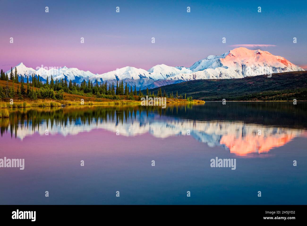 Sunset glow on Mount Denali (McKinley) reflects on Wonder Lake with pastel sky, Denali National Park and Preserve in autumn, Interior Alaska Stock Photo