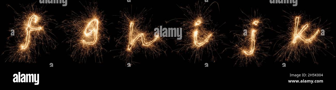 golden bright sparkler alphabet font letter set collection part F to K isolated on dark black background. silvester new year birthday and celebration Stock Photo