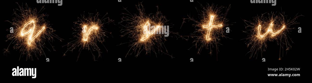 golden bright sparkler alphabet font letter set collection part Q to U isolated on dark black background. silvester new year birthday and celebration Stock Photo