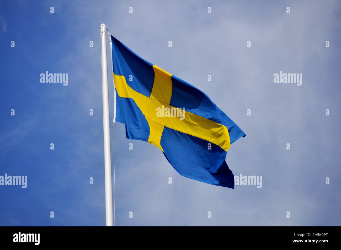 Flag of Sweden on pole against blue sky, Scandinavia Stock Photo