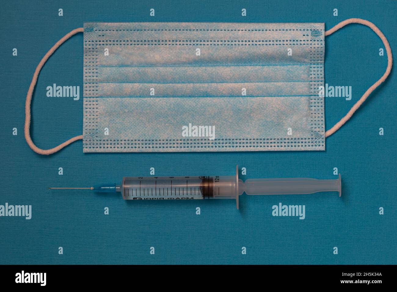 surgical mask and syringe on blue background Stock Photo - Alamy